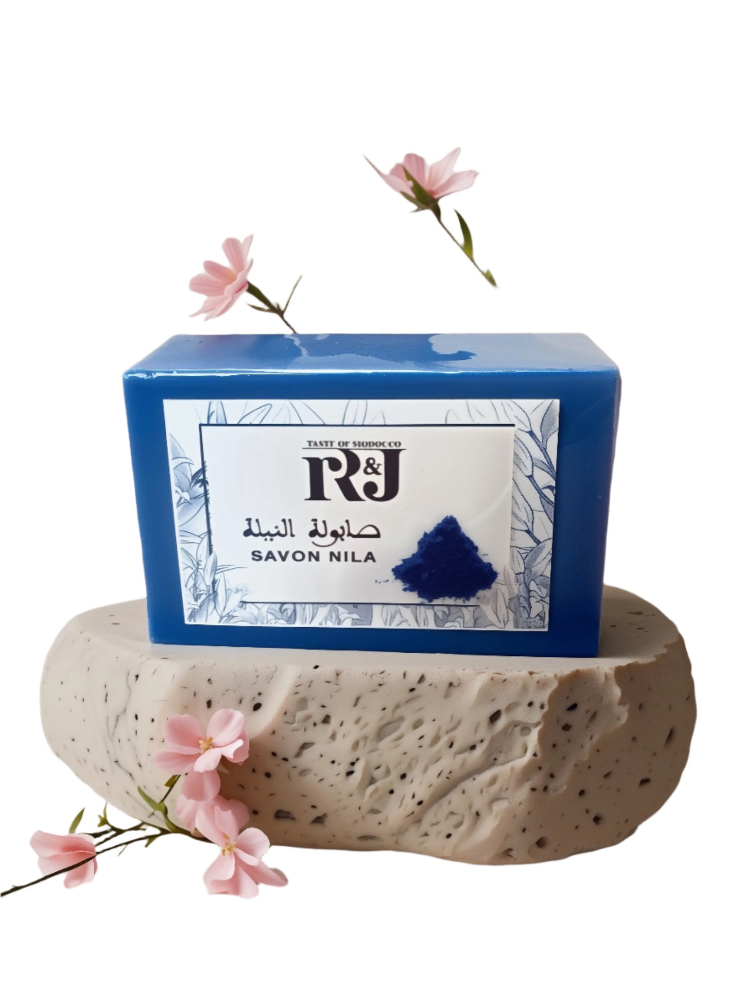 Blue soap bar with a white label on a stone surface with pink flowers. Soap made of natural Moroccan Nila