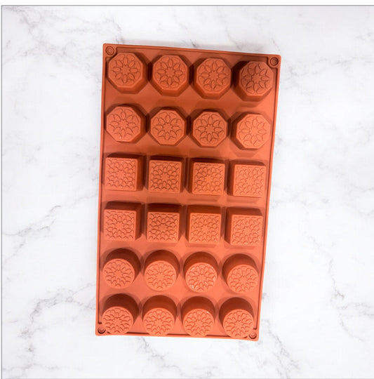 Orange silicone mold with various shapes on a white marble background